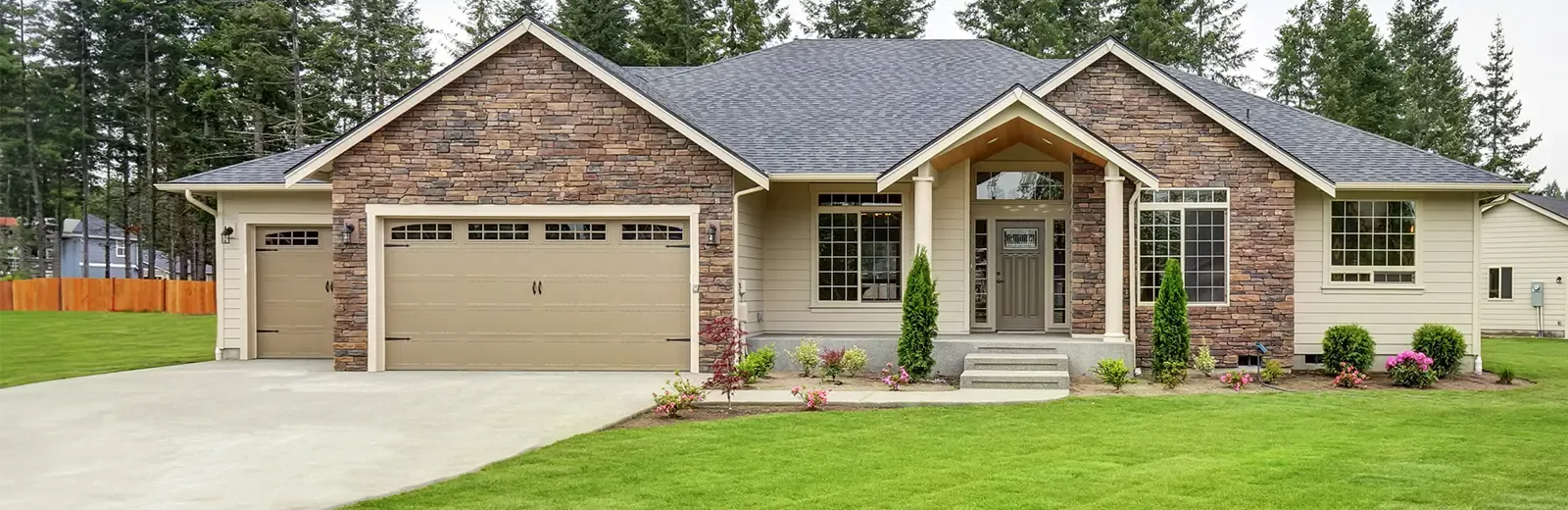 stone ranch house with nice green front lawn